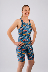 A woman modeling a one-piece athletic swimsuit with a blue background and a colorful print of koi fish, standing against a light gray studio background.
